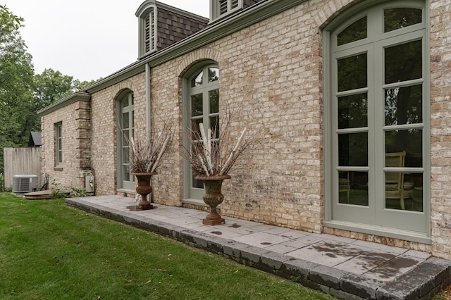 view of side of home with central AC, a yard, and brick siding