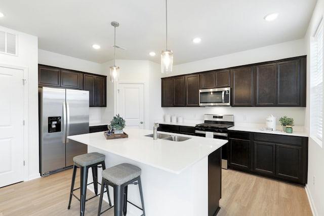 kitchen with pendant lighting, sink, dark brown cabinets, stainless steel appliances, and an island with sink