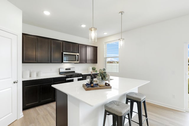 kitchen featuring a kitchen island, appliances with stainless steel finishes, a breakfast bar, pendant lighting, and dark brown cabinetry