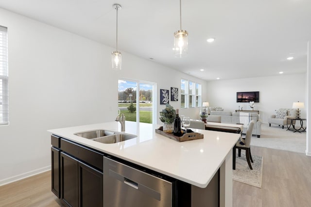 kitchen featuring sink, decorative light fixtures, dishwasher, an island with sink, and light hardwood / wood-style floors