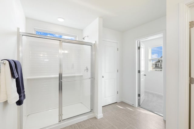 bathroom featuring a shower with shower door and a healthy amount of sunlight