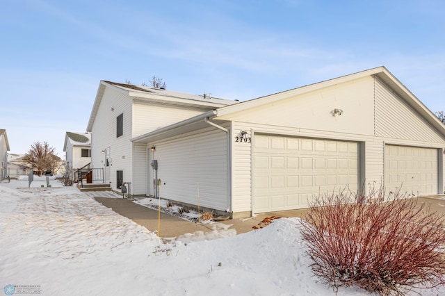 snow covered property with a garage