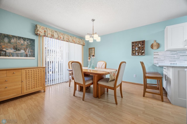 dining space with an inviting chandelier, light hardwood / wood-style flooring, and a textured ceiling