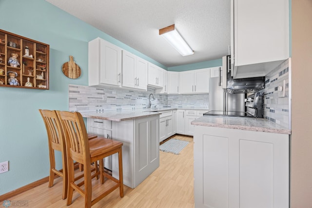 kitchen featuring white cabinetry, light stone counters, sink, and a breakfast bar area