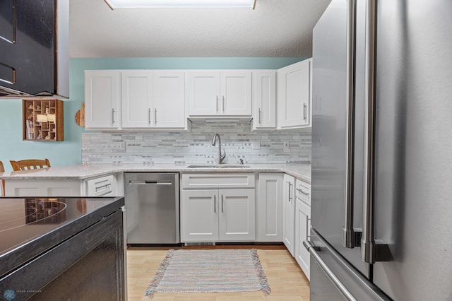 kitchen with white cabinetry, stainless steel appliances, light hardwood / wood-style floors, and sink