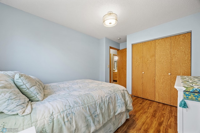 bedroom featuring wood-type flooring, a closet, and a textured ceiling