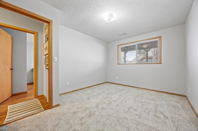 carpeted empty room featuring a textured ceiling