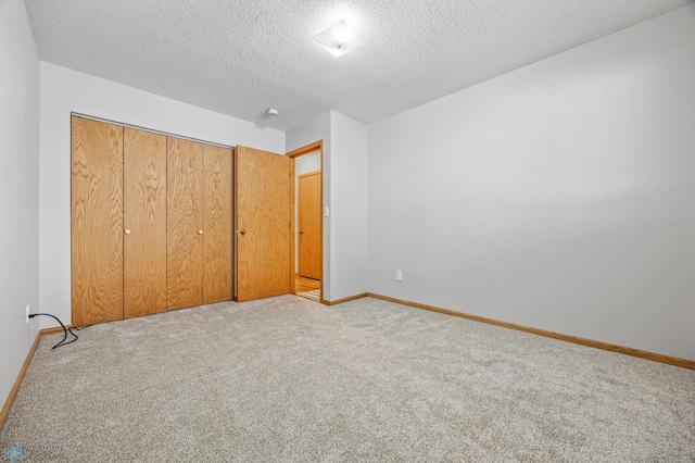 unfurnished bedroom featuring light carpet, a closet, and a textured ceiling