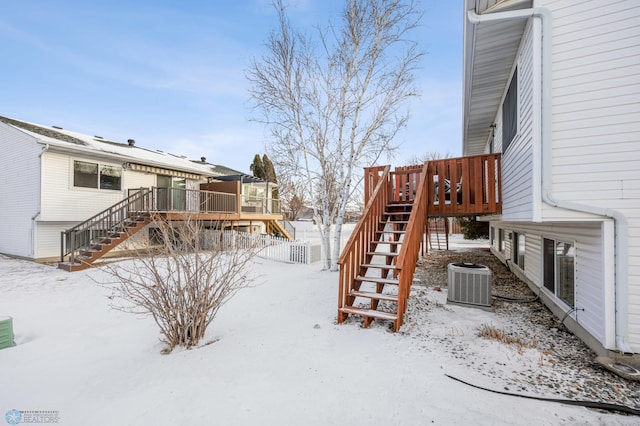 snowy yard featuring a wooden deck and central AC unit