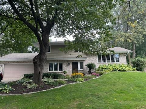 tri-level home featuring a garage and a front yard