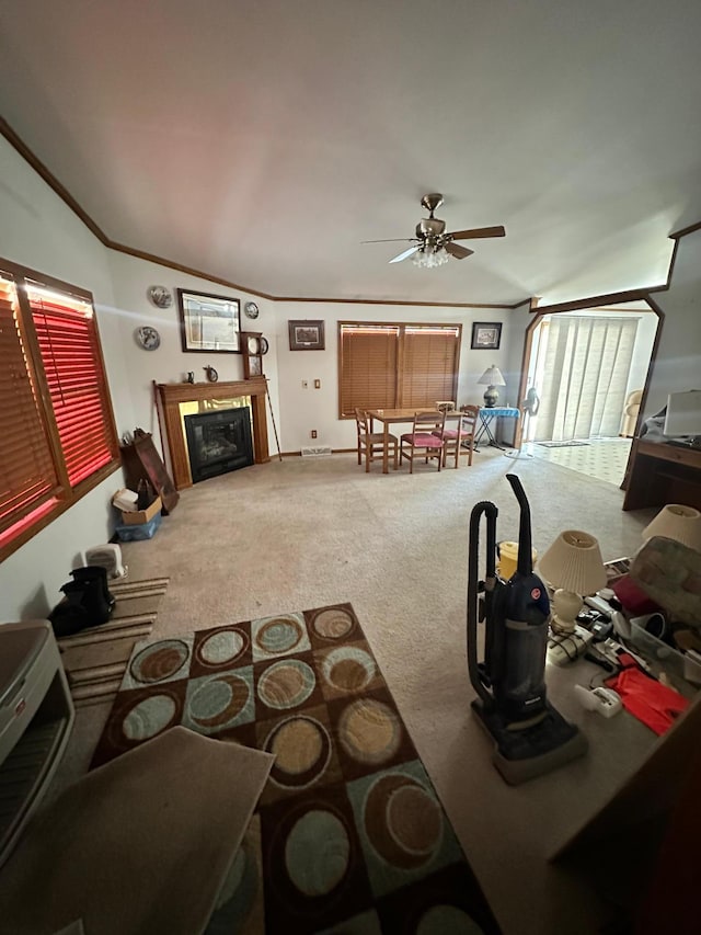 carpeted living area with ceiling fan, a glass covered fireplace, and ornamental molding