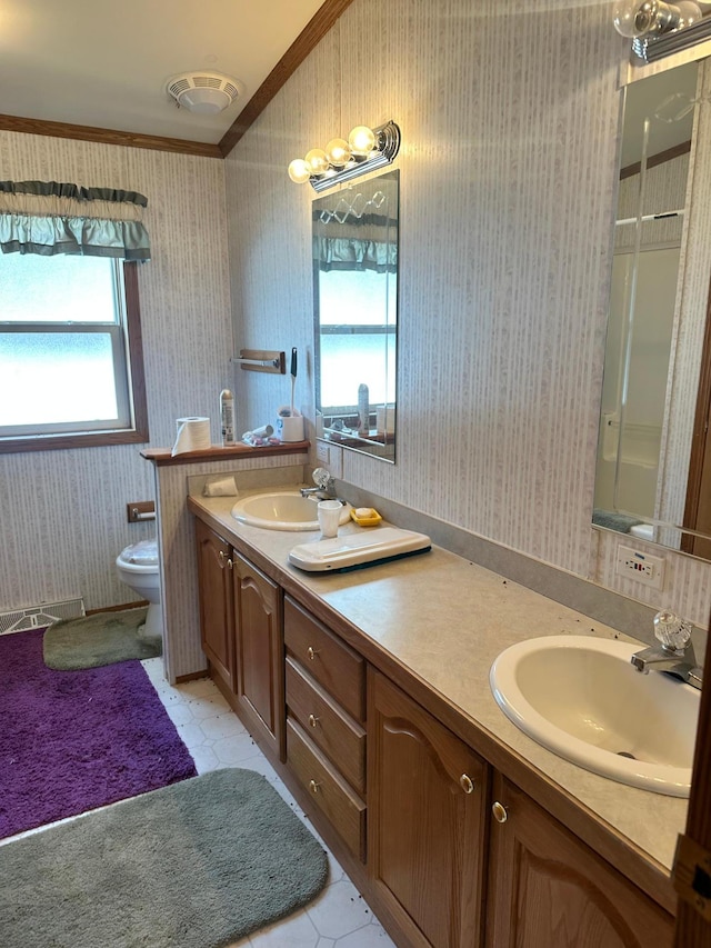 bathroom with double vanity, wallpapered walls, crown molding, and a sink