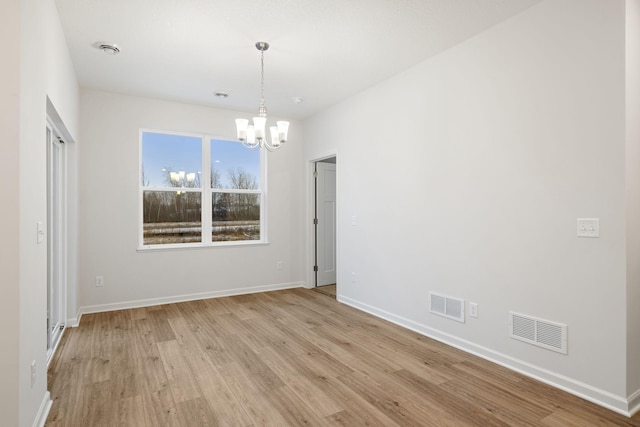 unfurnished room featuring light wood-type flooring and an inviting chandelier