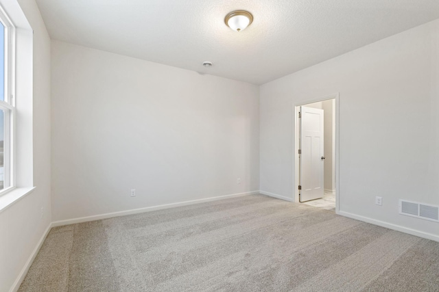 spare room featuring light carpet and a textured ceiling