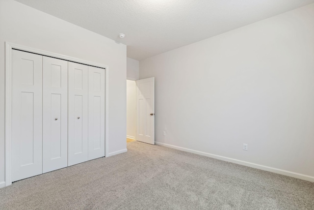 unfurnished bedroom with light colored carpet, a closet, and a textured ceiling