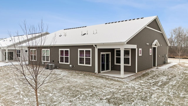 snow covered rear of property featuring central AC unit