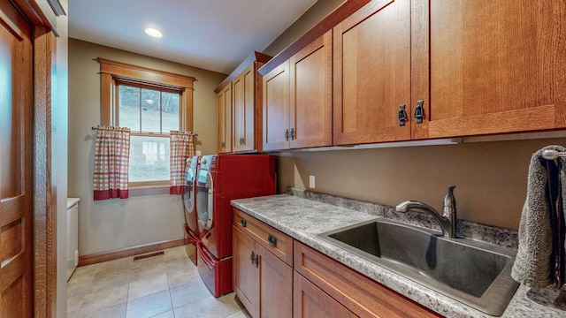 laundry room featuring independent washer and dryer, cabinets, sink, and light tile patterned floors