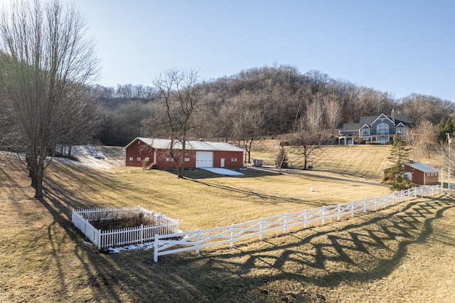 view of yard with a garage, an outbuilding, and a rural view