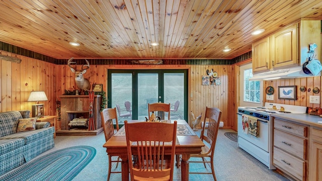 dining room with wooden walls, light colored carpet, a wealth of natural light, and wooden ceiling