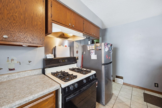 kitchen with light tile patterned floors, stainless steel refrigerator, gas range gas stove, a textured ceiling, and vaulted ceiling