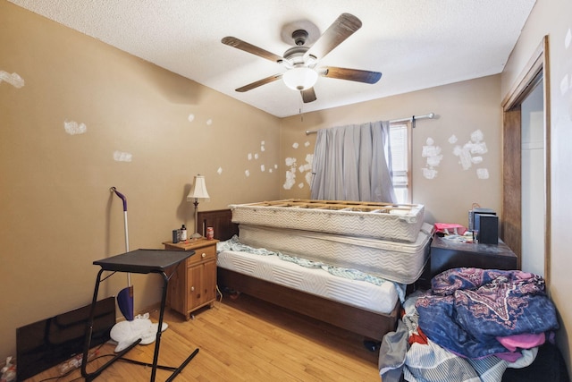 bedroom featuring a textured ceiling, ceiling fan, and light wood-type flooring