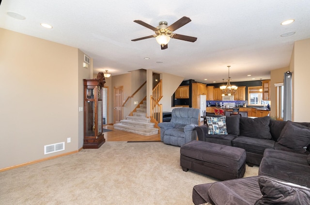 carpeted living room featuring ceiling fan with notable chandelier