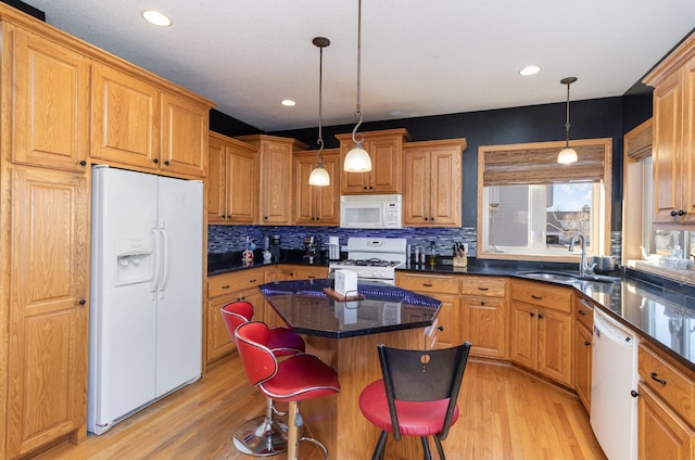 kitchen with sink, a kitchen breakfast bar, hanging light fixtures, a center island, and white appliances