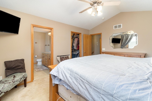 carpeted bedroom with lofted ceiling, connected bathroom, a walk in closet, a closet, and ceiling fan