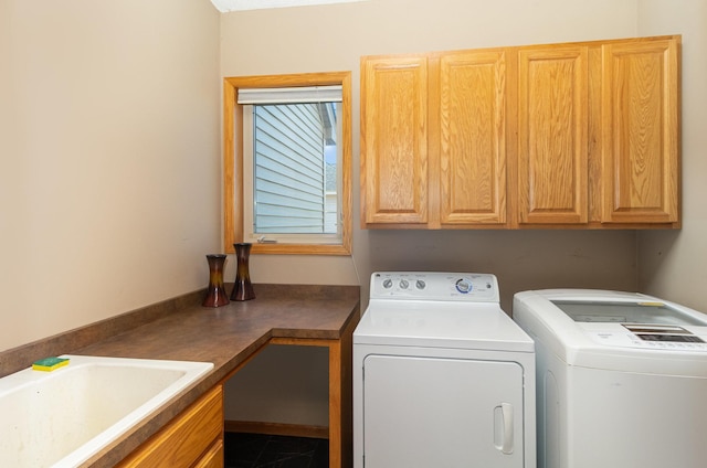 clothes washing area with independent washer and dryer, cabinets, and sink