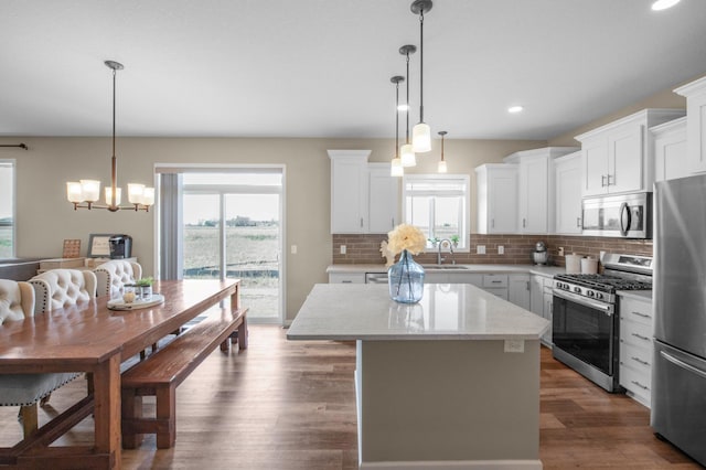 kitchen featuring hanging light fixtures, appliances with stainless steel finishes, a center island, and white cabinets