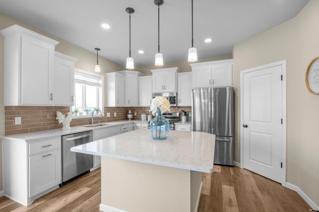 kitchen with white cabinetry, appliances with stainless steel finishes, a center island, and sink