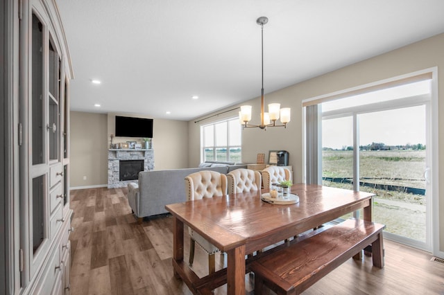 dining area with a stone fireplace, dark hardwood / wood-style floors, and a chandelier