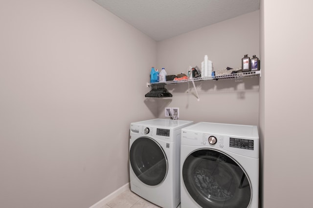 clothes washing area with light tile patterned floors, a textured ceiling, and washer and clothes dryer