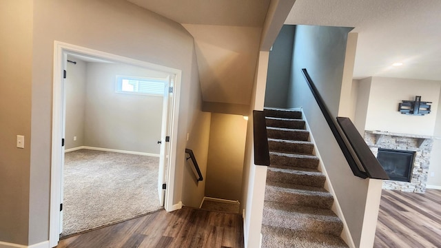 staircase with hardwood / wood-style flooring and a fireplace