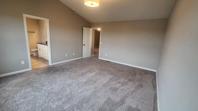 unfurnished bedroom with lofted ceiling, light colored carpet, and ensuite bathroom