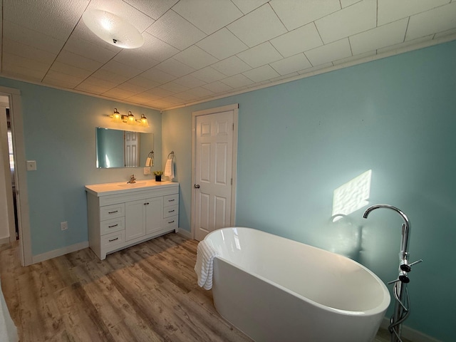 bathroom featuring a freestanding bath, wood finished floors, baseboards, and vanity
