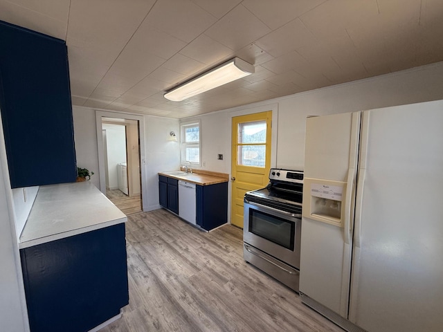 kitchen featuring blue cabinetry, a sink, white appliances, and light wood-type flooring