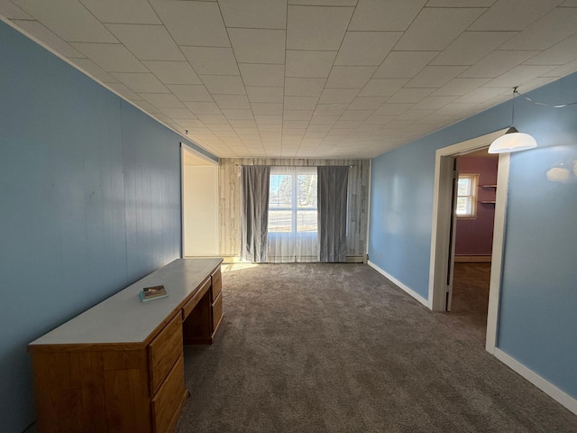 empty room featuring a baseboard radiator, dark colored carpet, and plenty of natural light
