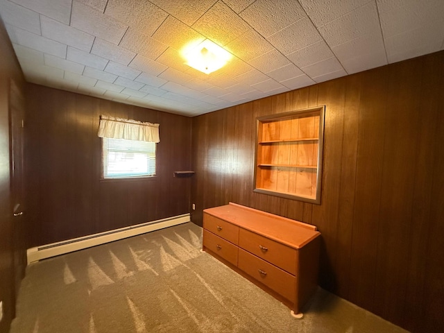 unfurnished bedroom with a baseboard radiator, wood walls, and carpet floors