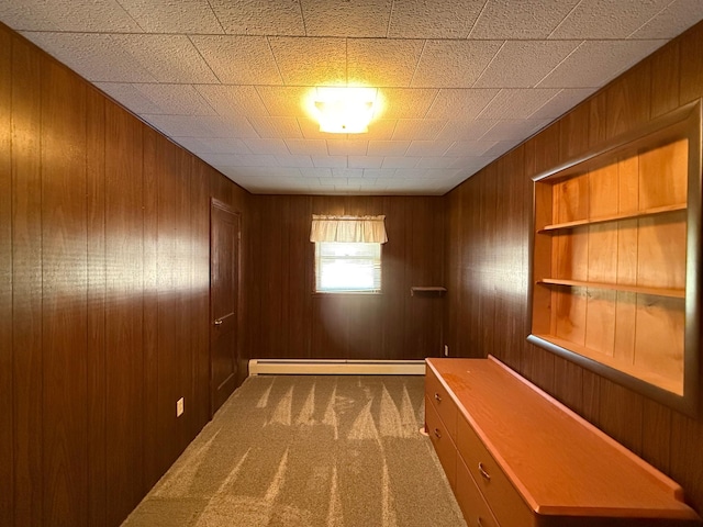 interior space with a baseboard heating unit, wood walls, and carpet floors
