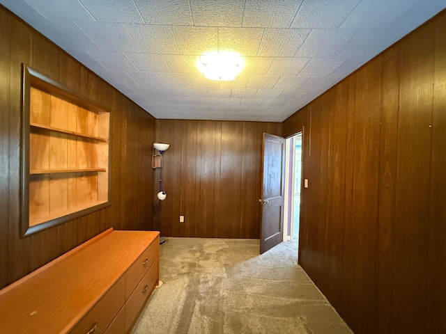 corridor with light carpet and wood walls