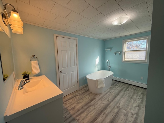 full bathroom featuring a baseboard radiator, wood finished floors, a freestanding tub, and vanity