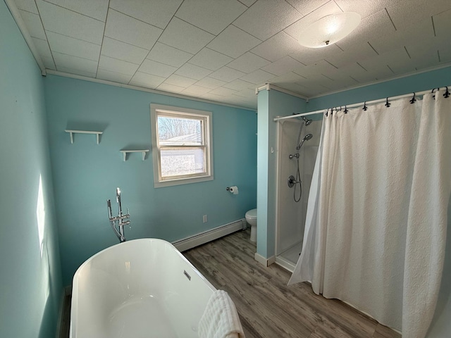 full bath with a baseboard heating unit, a freestanding bath, toilet, wood finished floors, and a shower with shower curtain