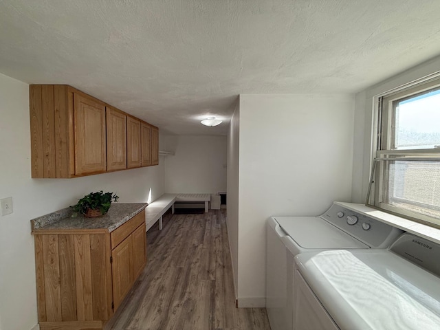 laundry area with washing machine and clothes dryer, wood finished floors, a textured ceiling, and cabinet space