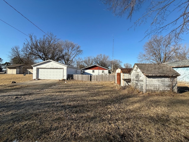 view of yard with an outdoor structure, fence, driveway, and a storage shed