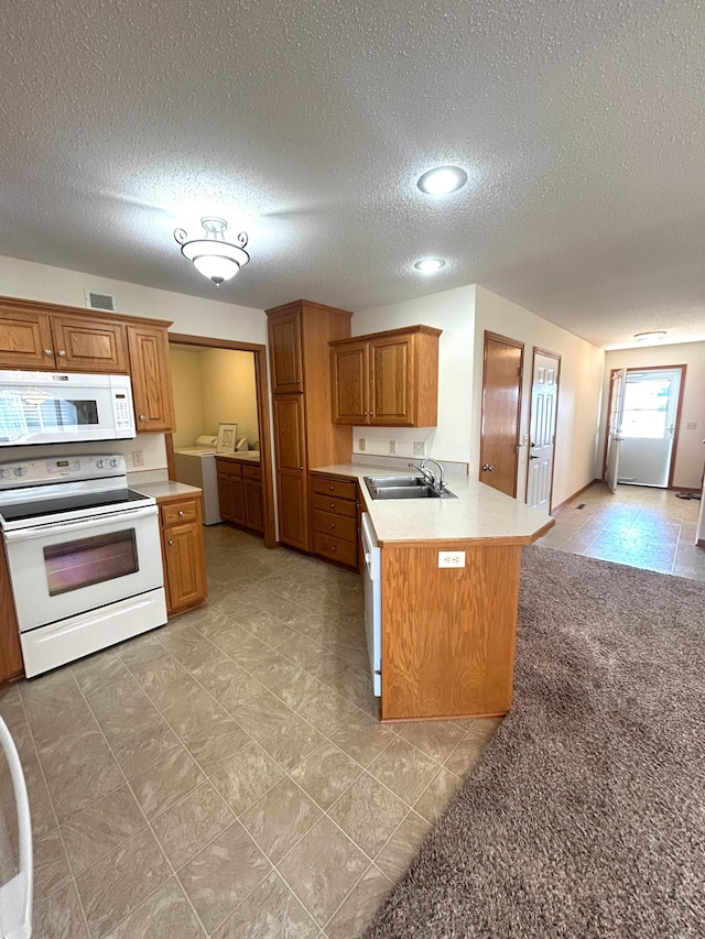 kitchen with sink, white appliances, light carpet, washer / dryer, and kitchen peninsula