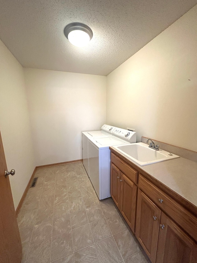 laundry room with sink, a textured ceiling, cabinets, and washing machine and clothes dryer