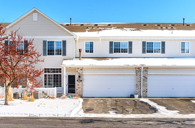 view of property featuring a garage, aphalt driveway, and brick siding