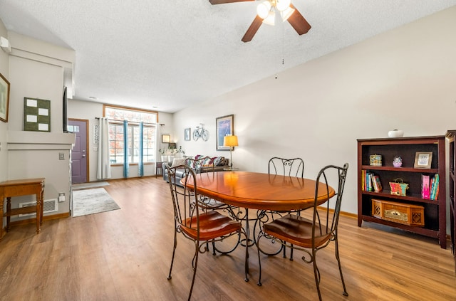 dining space with light wood-type flooring, ceiling fan, baseboards, and a textured ceiling