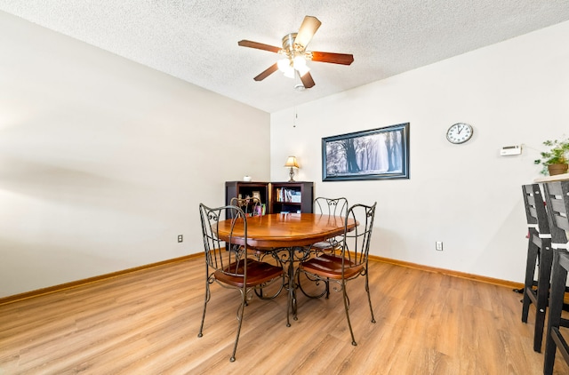 dining room featuring a ceiling fan, baseboards, light wood-style flooring, and a textured ceiling